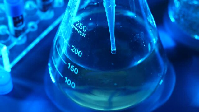 A dripper is dripping a liquid inside of a test tube in a laboratory