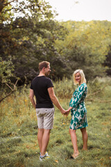 Obraz premium The happy pregnant couple is walking in the garden