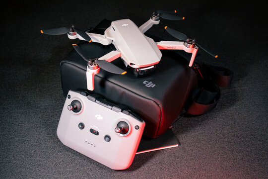 Kiev, Ukraine - February 02, 2021: Dji Mavic Mini 2 drone close-up. New unfolded quadcopter on black carrying bag with remote control on black background in red light