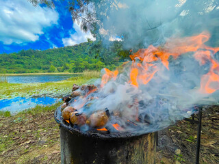 roasting meat and green chilies on a rustic barbecue, on the shore of a beautiful virgin lagoon with a beautiful sky © Mario