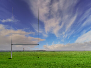 Irish sport tall goal posts in a field on a bright sunny day. Galway city, Ireland. South park. Camogie, hurling and rugby training ground. Blue cloudy sky. Selective focus
