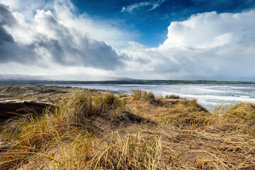 Sand dunes by the ocean. Blue cloudy sky. Nature background. Strandhill beach, Sligo, Ireland. Warm and sunny day