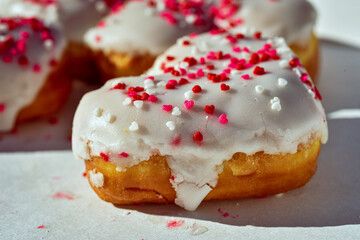 heart-shaped donuts with white icing and tiny red and white heart sprinkles sweet food for Valentines day