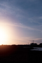 Fototapeta premium Silhouette of a construction site with modern technology building and tall crane at a sunset. Galway city, Ireland. Building new residential and commercial property concept