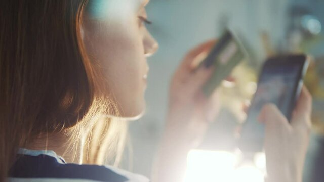 girl pays for purchases online shopping with a debit card in a smartphone. online store shop e-commerce concept. girl makes purchases in a web store with a debit card internet. online shopping