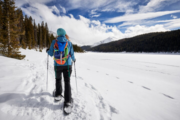a young woman hiking in the mountains on snowshoes.