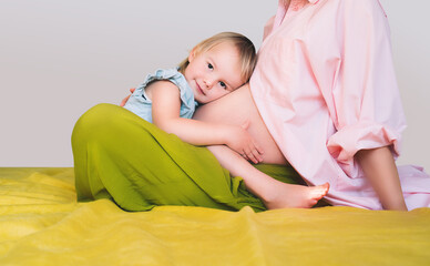 Pregnant mother and daughter together at home. Woman with her first child during second pregnancy....