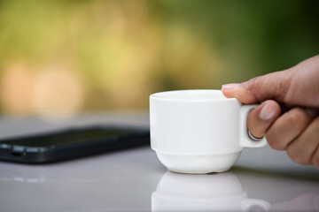 A cup of coffee on  table beside flower  in the morning. Cappuccino or espresso on table nature background in garden.