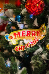 Merry Christmas sign on the christmas tree with ornaments.