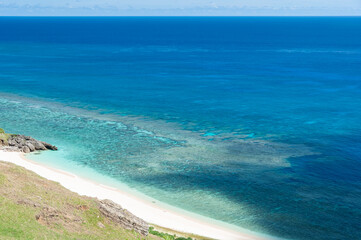 Fototapeta na wymiar Lush landscape seen from above the beautiful deserted beach with clear blue waters and a beautiful coral reef.