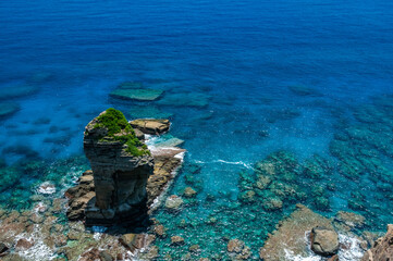 Impressive transparent blue sea seen from a cliff where you can see the famous Tategami Iwa stone surrounded by coral reefs. Yonaguni Island.