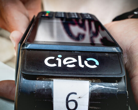 Cielo, máquina de cartão. Fotografia de um homem com uma máquina de cartão da empresa brasileira Cielo.	