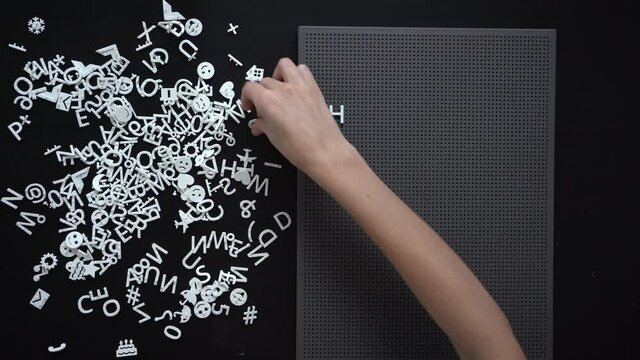 Thin female hand lays out words HOME on a dark grey board Sweet home Safe place concept. Home is where youre loved Copy space 
