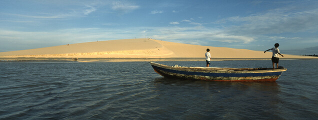 Foto panorâmica de crianças brincando em canoa na praia de Jericoacoara.