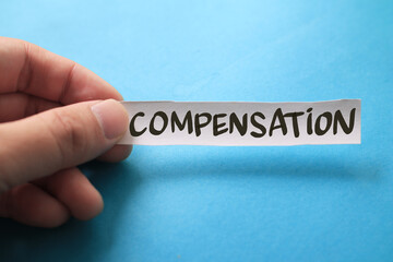 Compensation, text words typography written on paper against blue background, life and business motivational inspirational