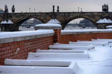 Fototapeta premium snowy brick wall and Charles Bridge in Prague on the Vltava river