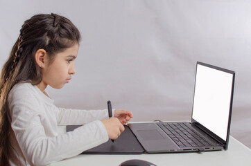 Girl drawing with a graphics tablet on a laptop, with light background, online art classes.