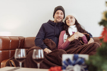 Young couple love sitting together and looking to outside on winter. Couple love in sweater enjoying and talking together. Happy couple in love on valentine night.