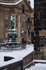 Fototapeta premium street light lamp on Charles Bridge and in the background a snow-covered statue of the monument to Charles 4 from the 18th century in Prague