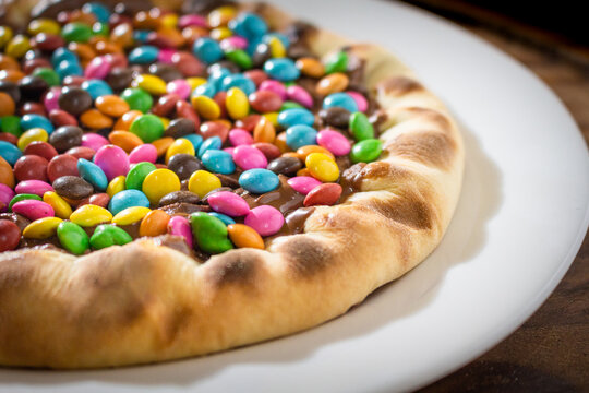 Pizza Doce com recheio de chocolate e peda&ccedil;os de chocolate coloridos.