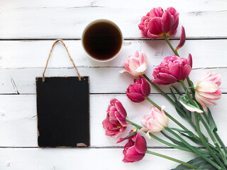 Bouquet of tulips with a cup of coffee and a blank chalkboard for text