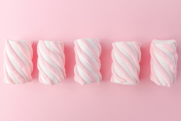 Row of pink and white marshmallows on pink background