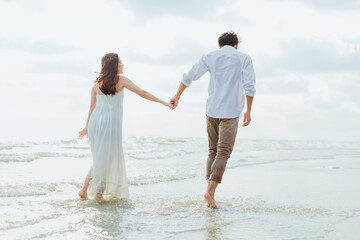 Love young couple holding hands and running on the beach. Holiday and vocation concept.