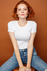 Obraz premium young pretty redhead girl posing cheerful on warm brown background, lifestyle people concept