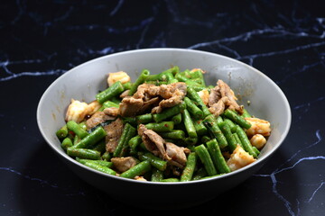 Spicy Fried and stirred cutting fresh green bean (Yardlong bean) with chicken and chilly paste serving on the plate. Famous appetizer menu in Chinese restaurant. 