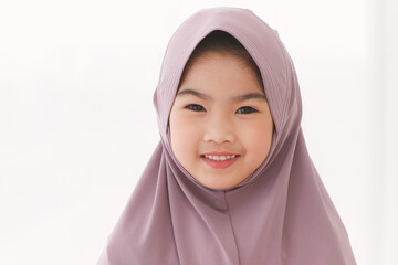 Portrait of 7s little Muslim girl wearing hijab traditional religious cloth looking to camera with lovely smile