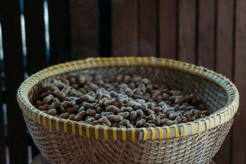 Freshly steamed peanuts sitting in a woven basket with steam rising off of them.