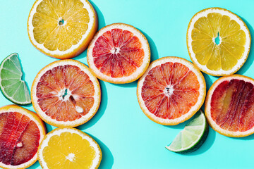 Composition with slices citrus fruits, grapefruit, red orange, lemon, lime on turquoise. Summer food flat lay with daylight.