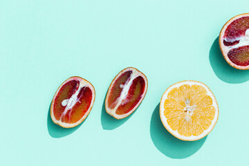 Composition with slices citrus fruits, grapefruit, red orange, lemon on turquoise. Summer food flat lay with daylight.