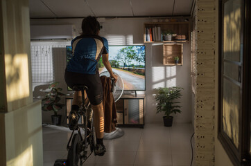 Fototapeta na wymiar Asian woman cyclist. She is exercising at home. She is playing games in the virtual world.