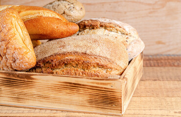 Various rustic crispy buns and bread in a box on a wooden background. Copy space, flat lay, space for text. Homemade baking. Close-up.
