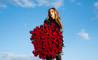 Girl with roses bouquet. Valentines day flower of love. Woman with rose bouquet outdoor. Lady and favorite flowers. Beautiful girl on sky background.