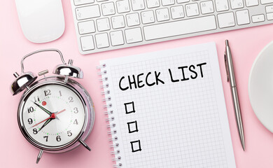 Pink workplace with computer, supplies, coffee and alarm