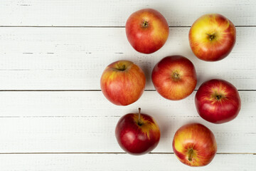 Delicious red apples on white wooden table with empty space.