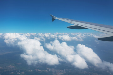 Fototapeta na wymiar Wing of airplane from window over fluffy clouds while traveling.