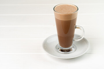 Glass cup of cocoa drink on white wooden table