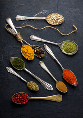 Various spices spoons on black table. Top view with copy space