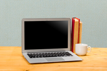 Laptop with blank screen, cup of coffee and books or notebooks on a wooden table. mockup for your text
