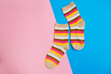 multicolored jersey socks on a pastel pink and blue background. view from above