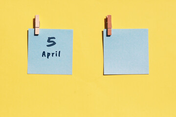 April 5st. Day of 5 month, calendar date. Two blue sheets for writing on a yellow background. Top view, copy space. Spring month, day of the year concept