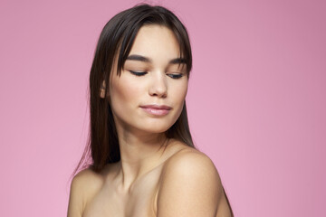 Woman with bare shoulders hair care makeup clean skin pink background