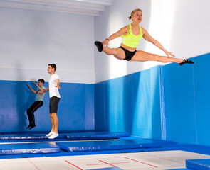 Indoor trampolines for adult people, positive young men and woman training in sports center