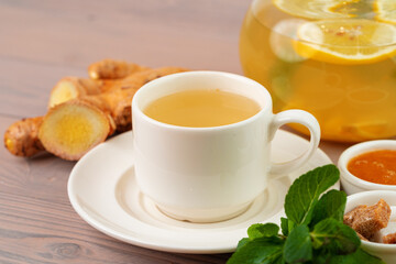 Cup of tea with ginger and mint on wooden table