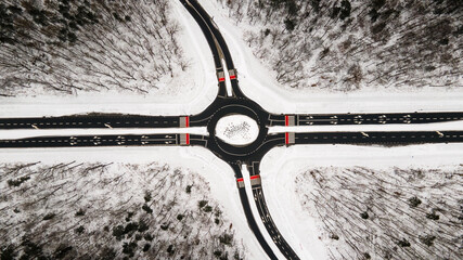 Crossroads in snow covered forest, top down aerial view.