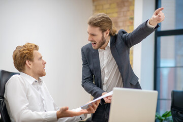 Screaming man pointing with hand and bewildered colleague