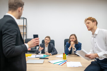 Serious men at table listening attentively to their colleague